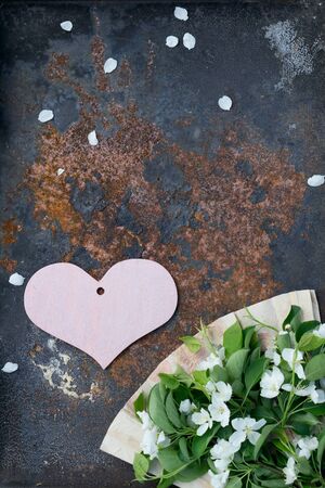 Valentine's Day card with wooden  pink heart , flower of apple with fan of handmade paperwork   against textured rustic iron  background の写真素材