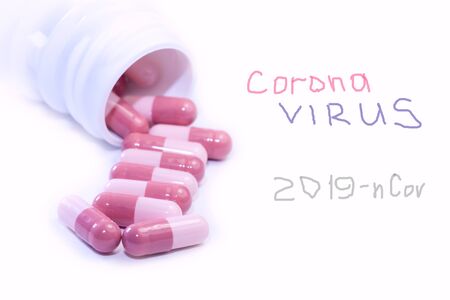 Coronavirus treatment concept with  pink arrow-shaped pharmaceutical medicine pills sprinkled from bottle over white background .の写真素材