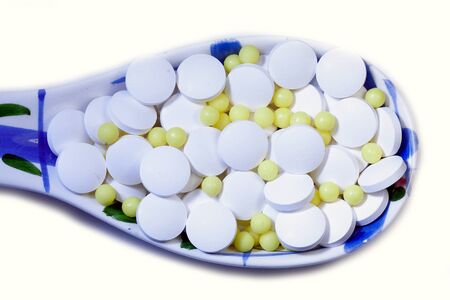 Corona virus treatment or diet concept glass  spoon with white
 and yellow
 pillsの写真素材