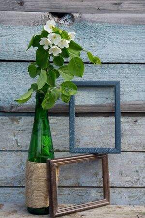 Creative top view apple tree blooming flowers brunch in green glass bottle  on  rustic wooden   background with copy space in minimal style, template for lettering, text or your designの写真素材