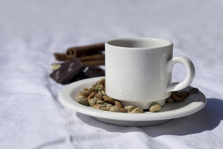 Coffee composition  with  white cup    of coffe  and beans of coffe, cinnamon, Chocolate,  on  linen tableclothtable as backgroundの写真素材