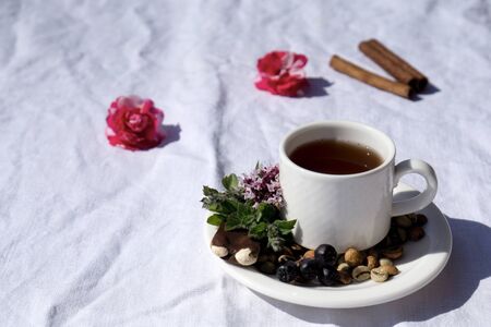 Coffee composition  with  white cup    of coffe with herb  and beans of coffe,  Chocolate,  berry, mint, flower on  linen tableclothtable as backgroundの写真素材