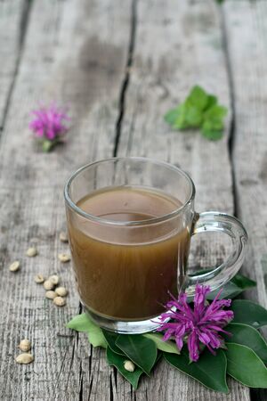 Coffee composition  with  glass  cup    of coffe with herb  and beans of coffe,   on rustic  wooden table  as backgroundの写真素材