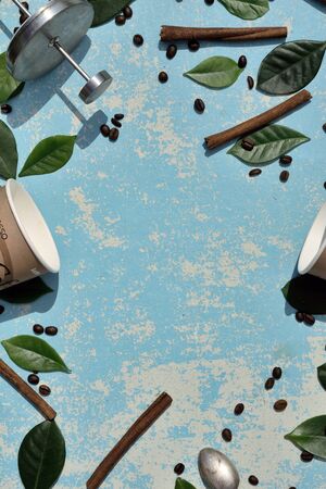 Flat lay  of coffee paper cup, pot,   brown coffee beans, green leaf and cinnamon on blue wooden as background with shadowの写真素材