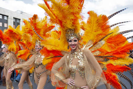 MOSCOW, RUSSIA - SEPTEMBER 01, 2012: Woman in fancy gold dress with feather on head go on prospectus...