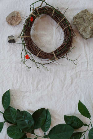 Easter consept with Crown of Thorns and green twig of tree, stone on white cloth background