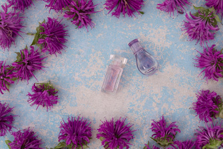 perfume bottle with violet bergamot flower on blue wooden background