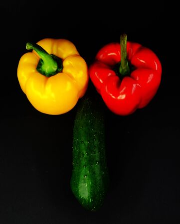 composition of the freakish form on a black background two peppers and cucumberの写真素材