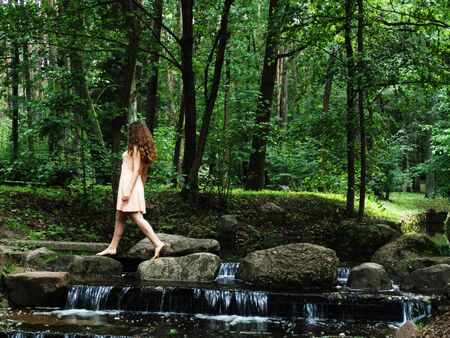she easily shifts from rock to rock over a small waterfallの写真素材