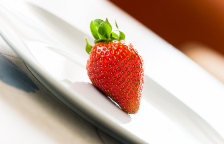 Single strawberry on a plateの写真素材
