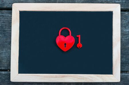 Table for Valentine's Day. Heart shaped red padlock with key on blackboardの写真素材