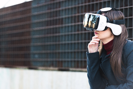 Handsome young woman using VR glasses with space for textの写真素材