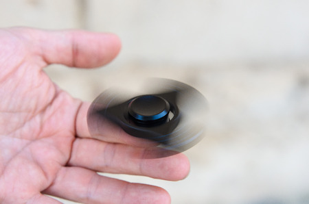 Playing with a Black Fidget Spinner. Metal spinnerの写真素材