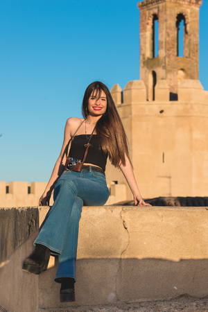 Beautiful young woman traveler with  camera front espantaperros tower in Badajoz.の写真素材