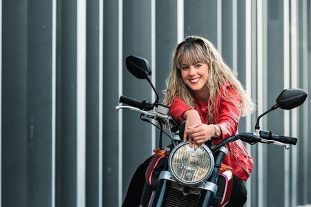 happy young woman mounting on a red motorbike