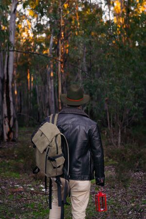 Mature man with hat and jacket entering into the forest