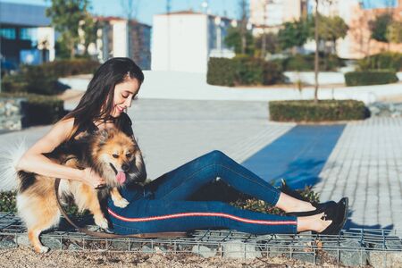attractive young  woman sitting with dog in the cityの写真素材
