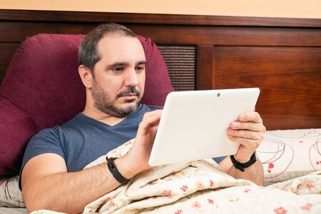 ill man using tablet in the bed.の写真素材