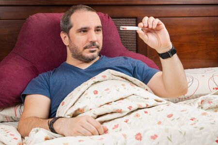 man in the bed with thermometerの写真素材