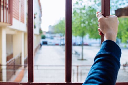 A woman's hand grabbing the bars of a window.の写真素材