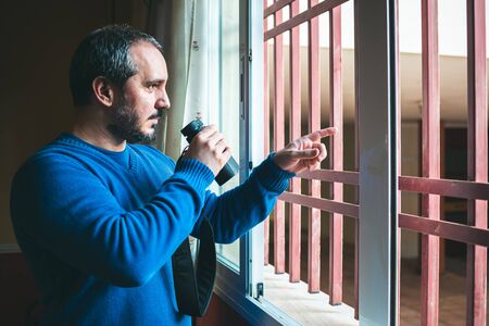 man watching the neighbors through the window during quarantineの写真素材