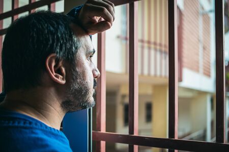 Close up portrait of man leaning out the window in the coronavirus quarantineの写真素材