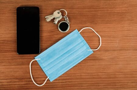 keys, medical mask and smartphone on a table. Top viewの写真素材