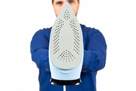 man in a blue shirt holding an iron on white backgroundの写真素材