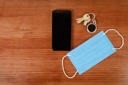 keys, medical mask and smartphone on a table. Top viewの写真素材