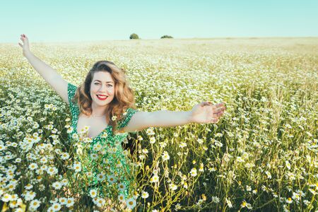 woman with open arms in a field of daisiesの写真素材