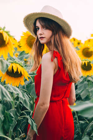 woman with red dress and hat in sunflowers fieldの写真素材