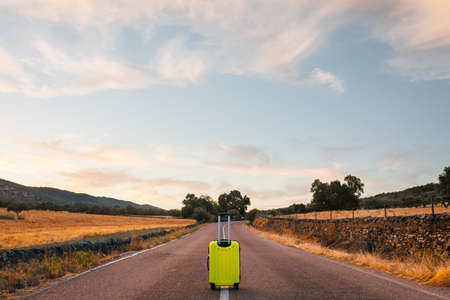 yellow suitcase on a road in the fieldの写真素材