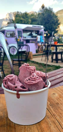 Roll ice cream in the mountains with spoon and foodtruck in the backgroundの写真素材