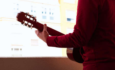 Boy playing guitar for his neighbors during coronavirus quarantine. Coronavirus conceptの写真素材