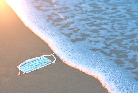 Protective face mask on the beach floor ready to be worn by a wave.Coronavirus waste. Covid 19...