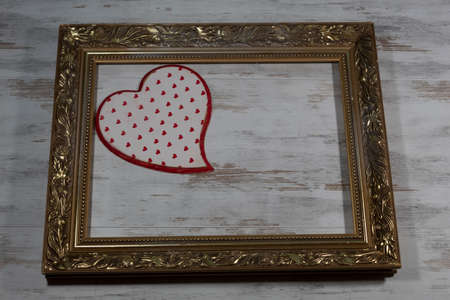 Festive background for Valentine's Day. In an old, gilded frame on a wooden background in the upper...