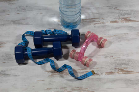 Healthy lifestyle concept. There are fitness items on the table - two dumbbells entwined with a...