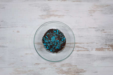 Close-up. View from above. On the table on a transparent saucer, a delicious cake decorated with...