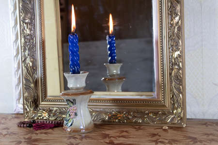 Fortune telling with a candle and a mirror. In the candlestick there is a burning candle, next to the rosary. The candle is reflected in the mirror.の写真素材