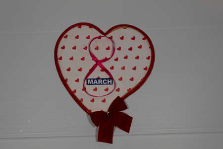 On a white background, a big heart, a red bow, the number 8 from the red ribbon and the word March.
