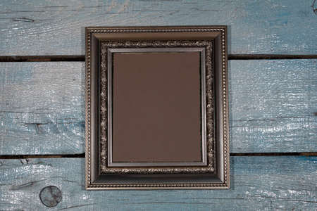 Background, texture. Close-up. On a painted plank background is a vertically silver picture frame with a brown middle.の写真素材