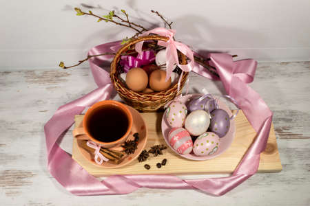 View from above. The composition is framed by a pink ribbon. On the table is a cup of tea, next to a...