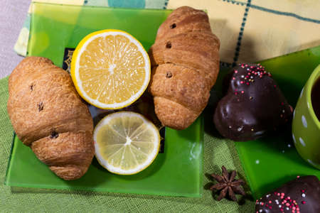View from above. Croissants and lemon lie on a green saucer. Nearby lies cookies and star anise.の写真素材