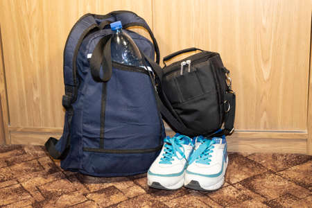 On the floor is a packaged backpack with an eggplant in your pocket and sneakers. Near the case with...
