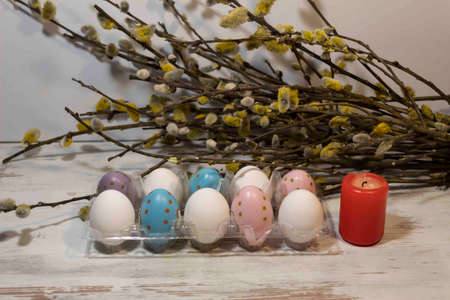 Easter eggs are in the tray. Nearby is a candle. There are willow branches behind.の写真素材