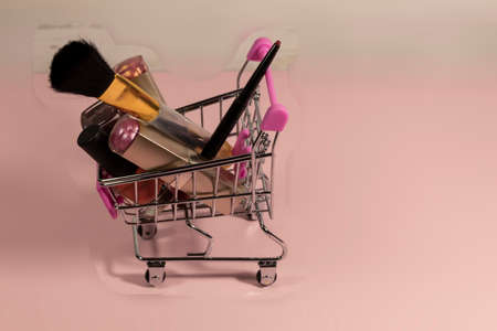 Blurred background. In the shopping trolley lies women's cosmetics: lipstick, nail polish, lip liner and brush.
の写真素材