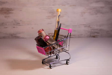 In the shopping trolley lies women's cosmetics: lipstick, nail polish, lip liner, brush.の写真素材