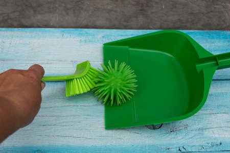 A hand holding a brush sweeps a mock coronavirus onto a scoop.の写真素材