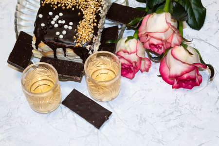 View from above.There are three roses on the table, two crystal glasses with wine. There is cake and chocolate on a platter.の写真素材