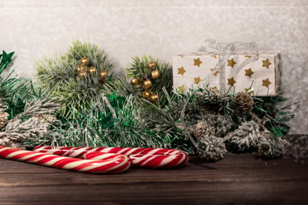 On a wooden background lies New Year's tinsel, spruce branches, a gift box and Santa Claus staffs.の写真素材